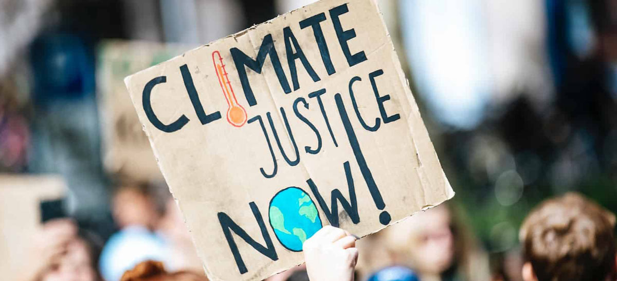 hand holding climate-justice-now sign